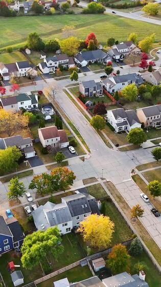 Aerial View of Suburban Neighborhood in Fall Vibrant aerial view of a suburban neighborhood with colorful autumn trees, neatly arranged houses, and winding